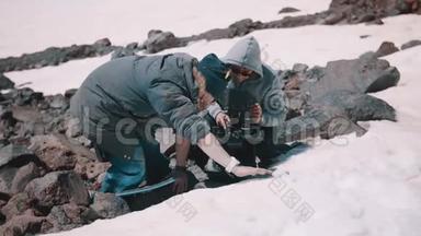 两名<strong>拍摄</strong>人员在<strong>雪山</strong>悬崖的防水垫上放置摄像机